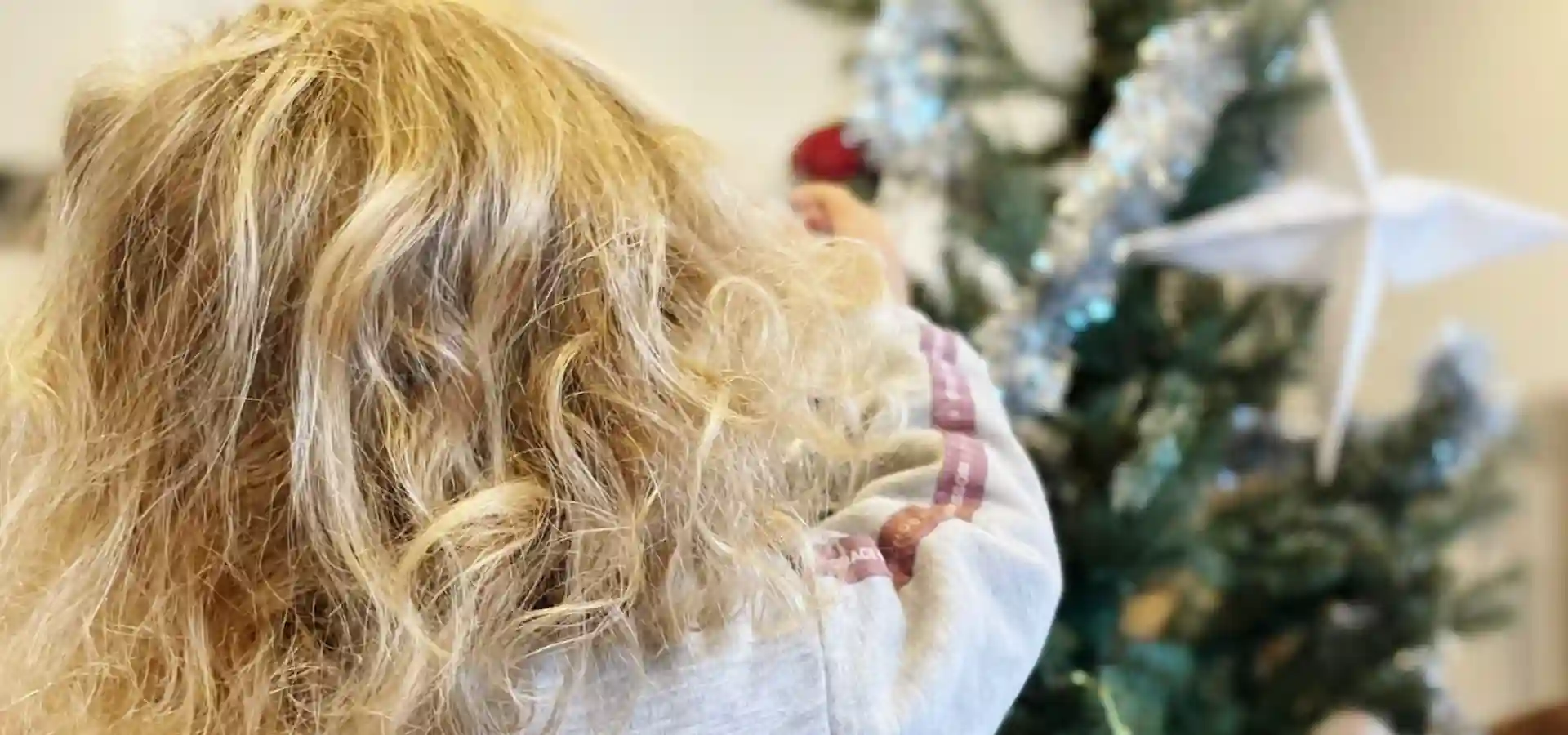 niña poniendo bolas en árbol Navidad